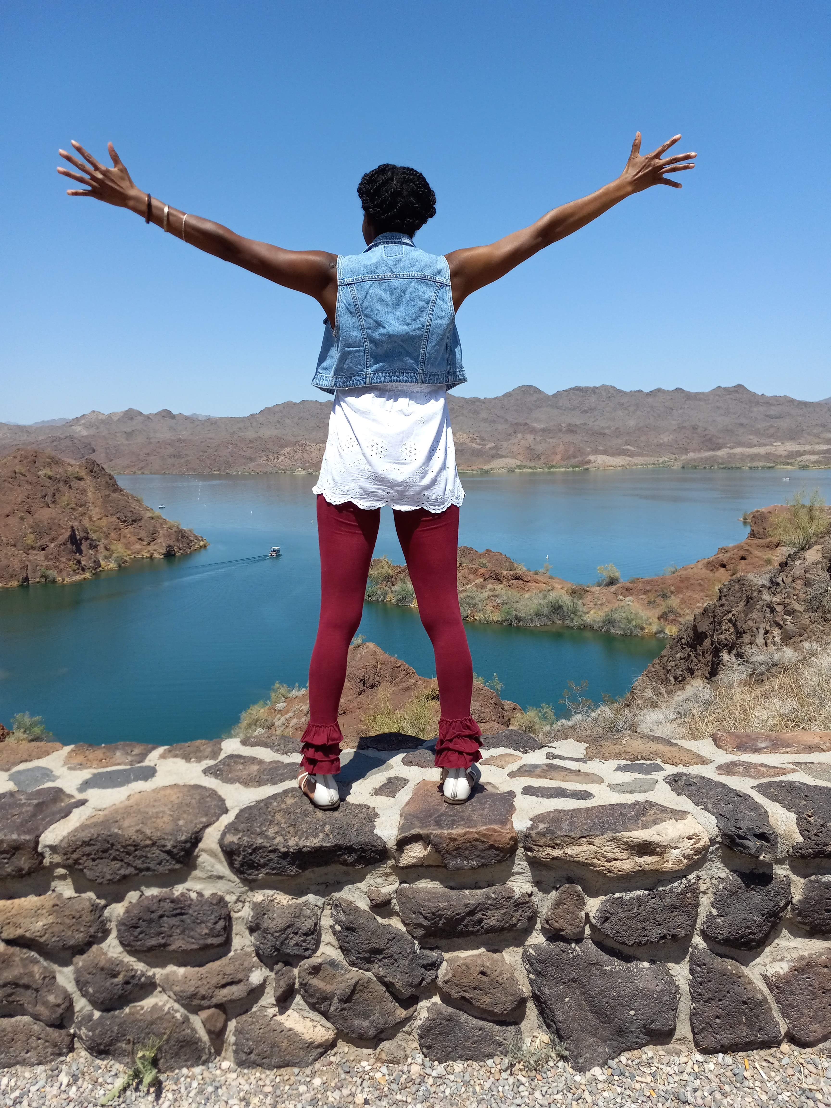 A woman standing on rocks with arms raised in celebration, embracing a new season